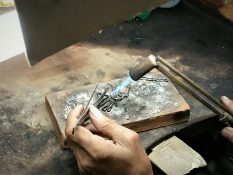 Lehim tuğlası üzerinde alevle birleştirilen takı parçaları